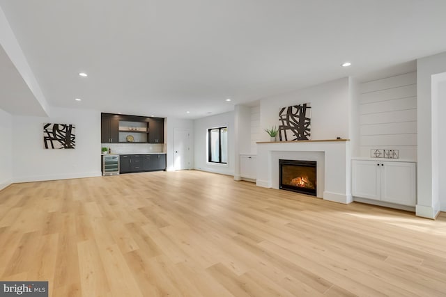 unfurnished living room with light hardwood / wood-style floors and beverage cooler