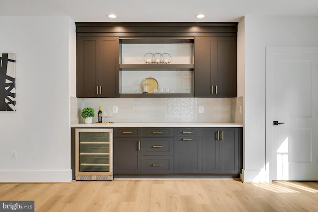 bar featuring wine cooler, light hardwood / wood-style flooring, gray cabinets, and tasteful backsplash