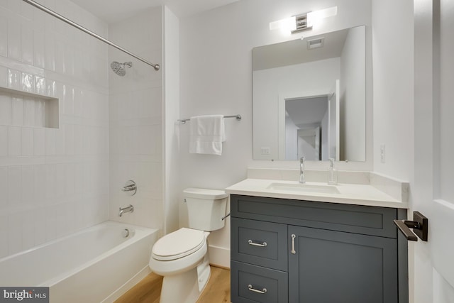 full bathroom with vanity, toilet, tiled shower / bath, and hardwood / wood-style floors