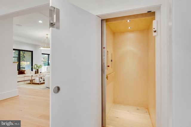 hall with hardwood / wood-style flooring and elevator