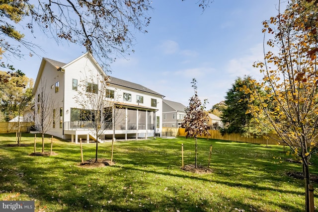 back of property with a sunroom and a lawn