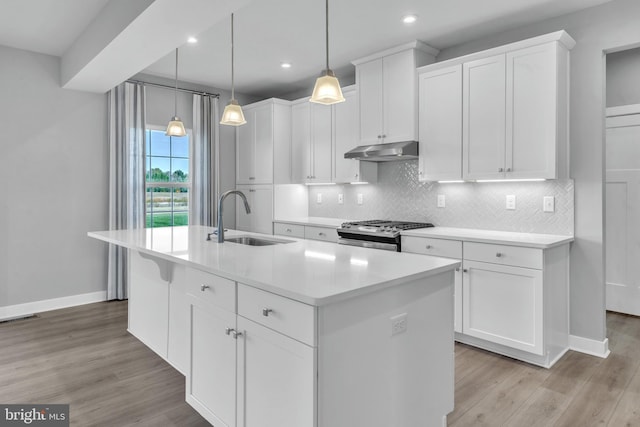 kitchen featuring tasteful backsplash, sink, an island with sink, white cabinets, and stainless steel gas range