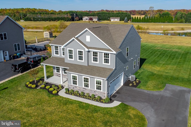 view of front of house featuring a water view, a front lawn, central AC unit, and a garage