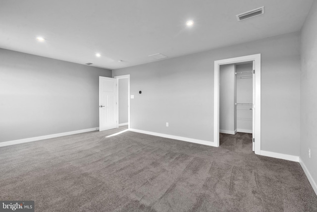 unfurnished bedroom with a closet, a spacious closet, and dark carpet