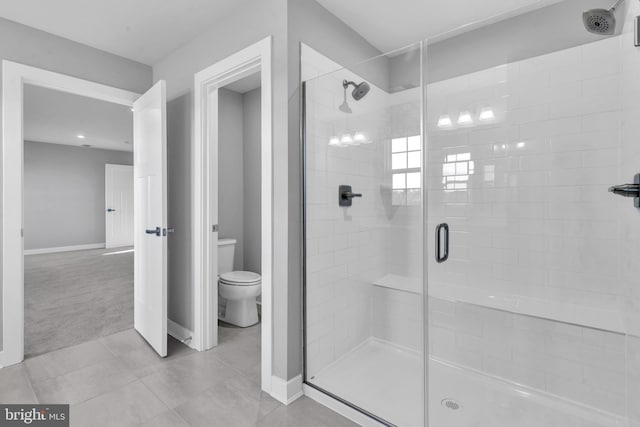 bathroom featuring a shower with door, toilet, and tile patterned flooring