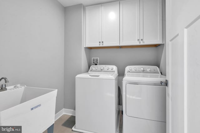 clothes washing area with sink, washer and dryer, and cabinets