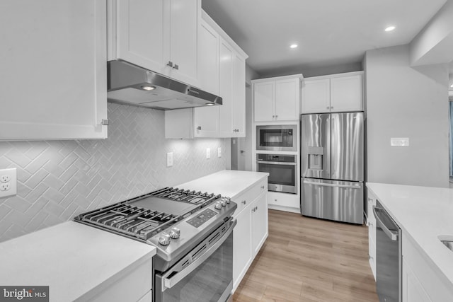 kitchen with white cabinetry, backsplash, appliances with stainless steel finishes, and light hardwood / wood-style flooring