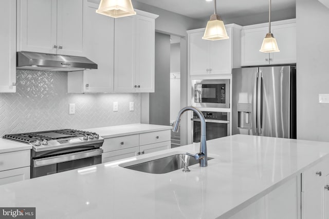 kitchen with white cabinetry, sink, range hood, decorative light fixtures, and stainless steel appliances