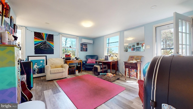 home office featuring light hardwood / wood-style floors, a wall unit AC, and a healthy amount of sunlight