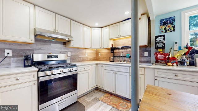 kitchen with light hardwood / wood-style flooring, white cabinetry, sink, and stainless steel gas stove