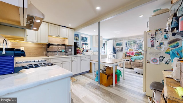 kitchen featuring tasteful backsplash, white cabinetry, light wood-type flooring, white fridge, and sink