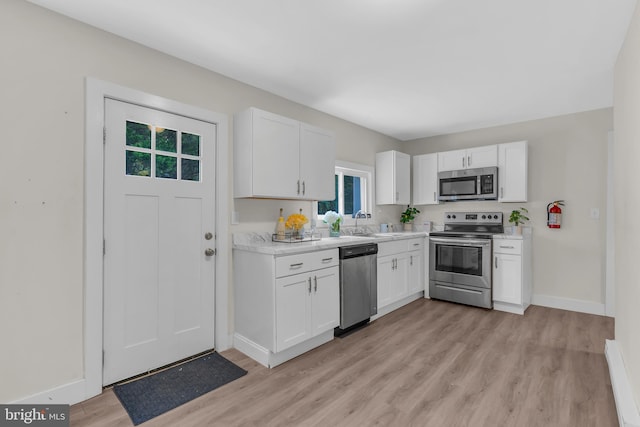 kitchen featuring stainless steel appliances, a baseboard heating unit, light wood-type flooring, and white cabinets