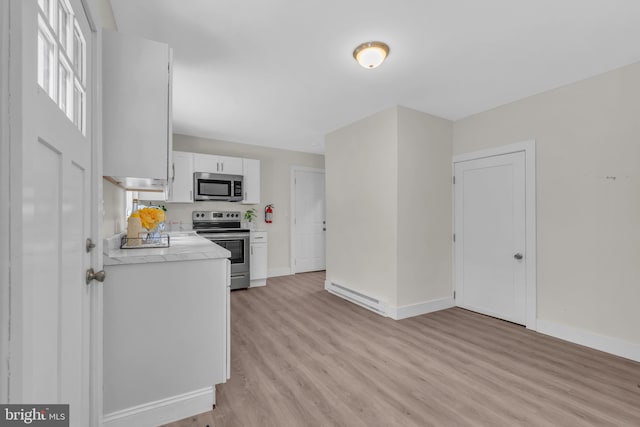 kitchen featuring appliances with stainless steel finishes, light wood-type flooring, and white cabinets