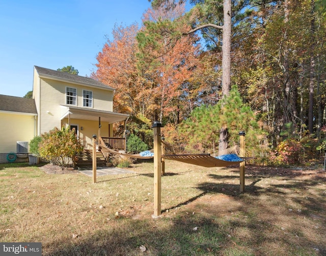 rear view of house featuring central AC unit and a lawn