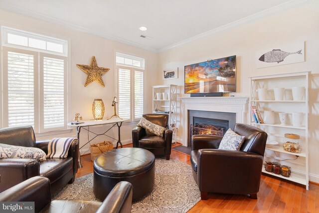 living area with hardwood / wood-style floors and ornamental molding