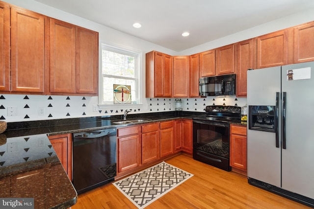 kitchen featuring decorative backsplash, light hardwood / wood-style floors, black appliances, and sink