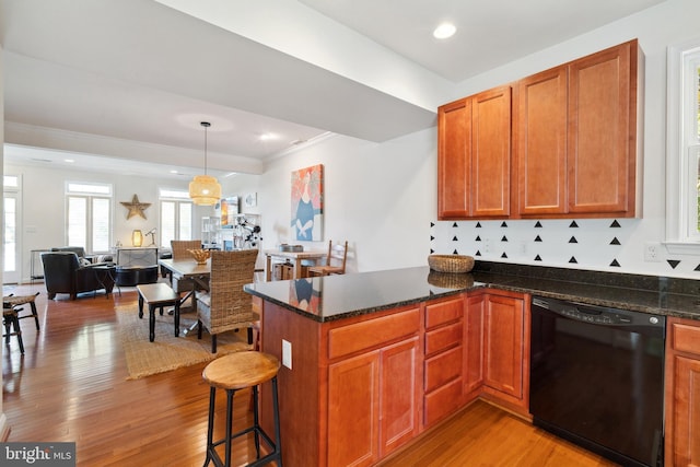 kitchen featuring dishwasher, light wood-type flooring, a kitchen breakfast bar, and pendant lighting