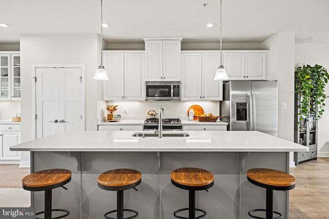 kitchen with white cabinetry, light wood-type flooring, appliances with stainless steel finishes, and a center island with sink