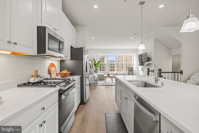 kitchen with stainless steel appliances, white cabinetry, sink, and pendant lighting