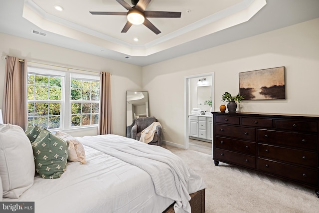 bedroom with connected bathroom, light colored carpet, ceiling fan, and a raised ceiling