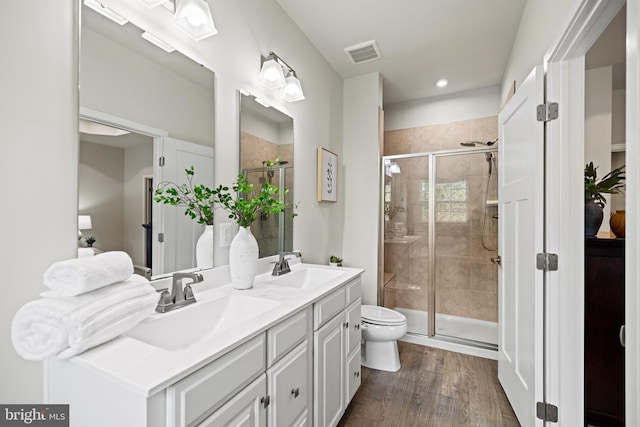 bathroom featuring toilet, vanity, hardwood / wood-style flooring, and a shower with shower door