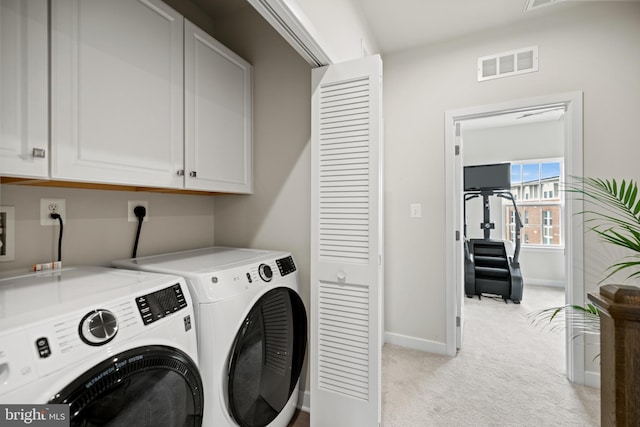 clothes washing area with light colored carpet, cabinets, and washer and dryer