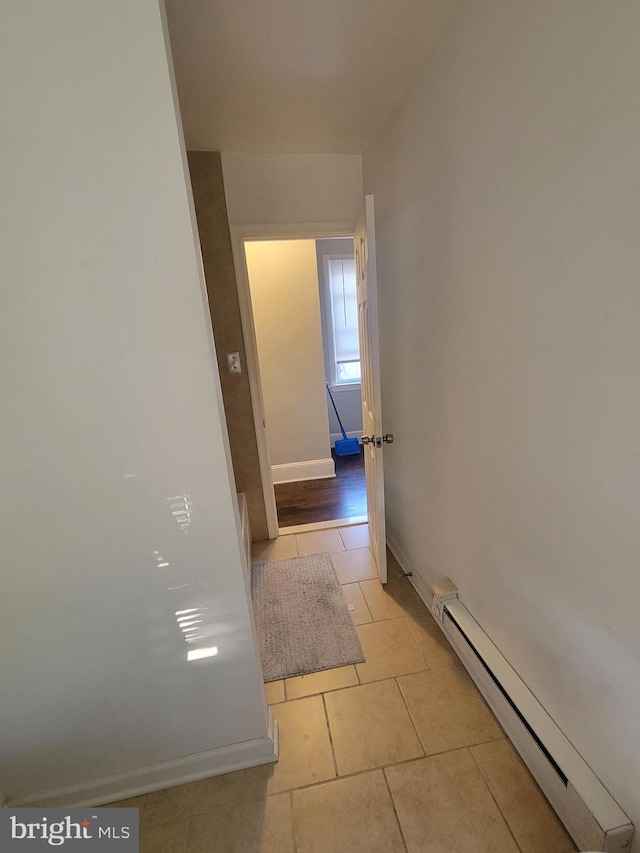 corridor featuring a baseboard heating unit and light tile patterned floors