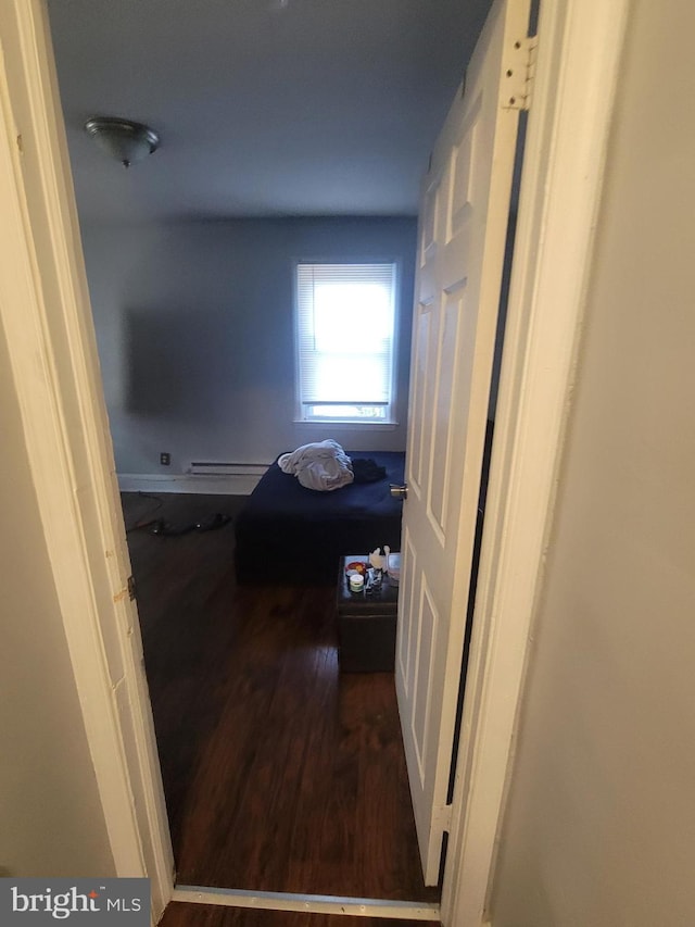 hall with dark wood-type flooring and a baseboard heating unit