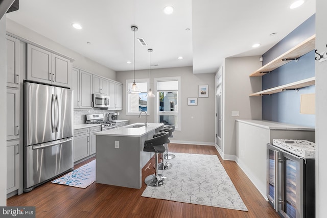 kitchen featuring gray cabinetry, stainless steel appliances, dark hardwood / wood-style floors, and a kitchen island with sink