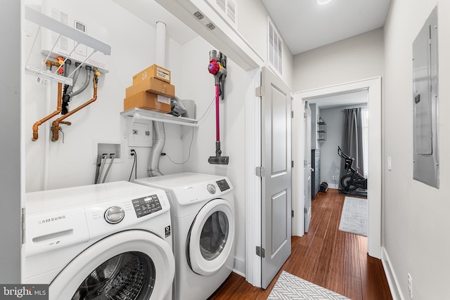 washroom with dark wood-type flooring, washer and clothes dryer, and electric panel