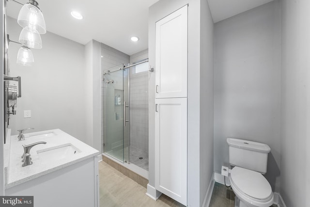 bathroom featuring toilet, a shower with shower door, and vanity