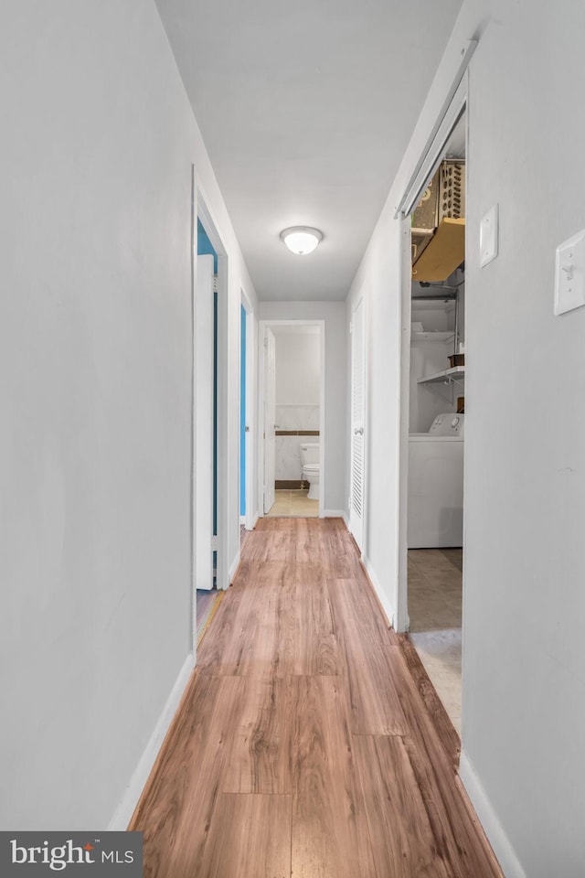 hallway with washer / clothes dryer and light hardwood / wood-style flooring