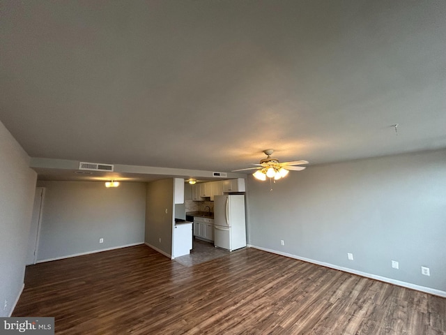 unfurnished living room featuring ceiling fan and dark hardwood / wood-style flooring