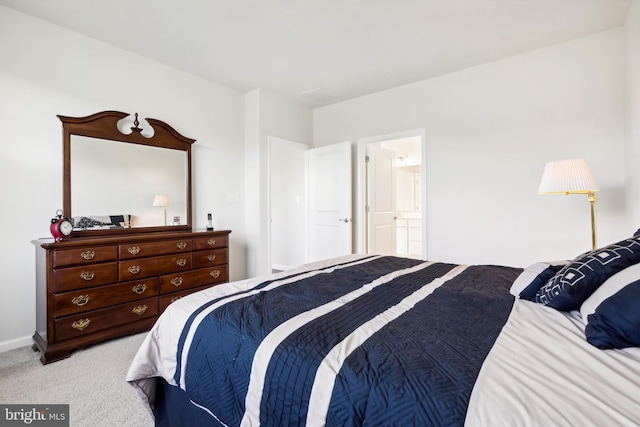 bedroom with ensuite bathroom and light colored carpet