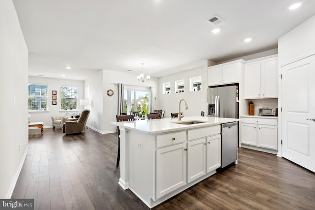 kitchen with white cabinets, stainless steel appliances, sink, and an island with sink