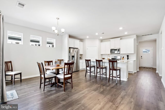 dining area featuring a wealth of natural light, dark hardwood / wood-style flooring, sink, and an inviting chandelier