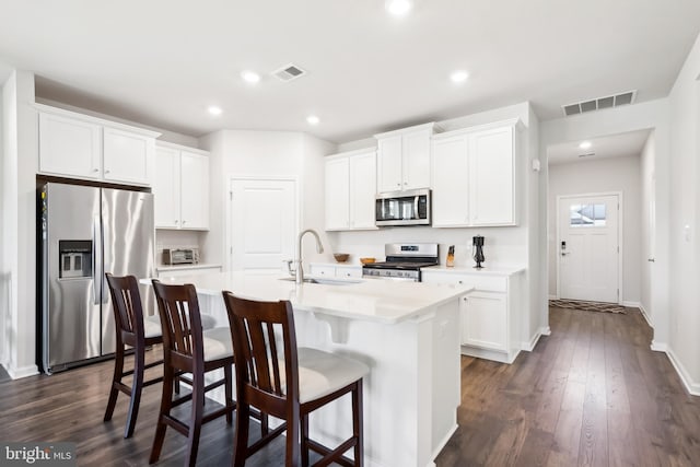 kitchen featuring stainless steel appliances, white cabinets, sink, and a center island with sink