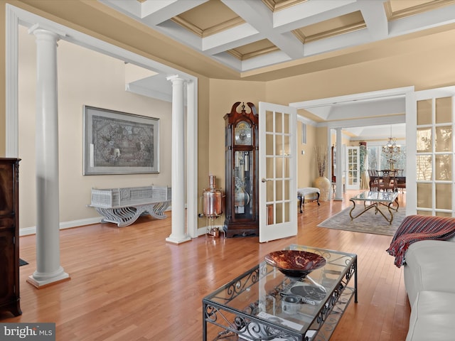 living area featuring ornamental molding, coffered ceiling, decorative columns, and wood finished floors