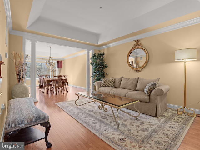 living area featuring hardwood / wood-style floors, a raised ceiling, and decorative columns