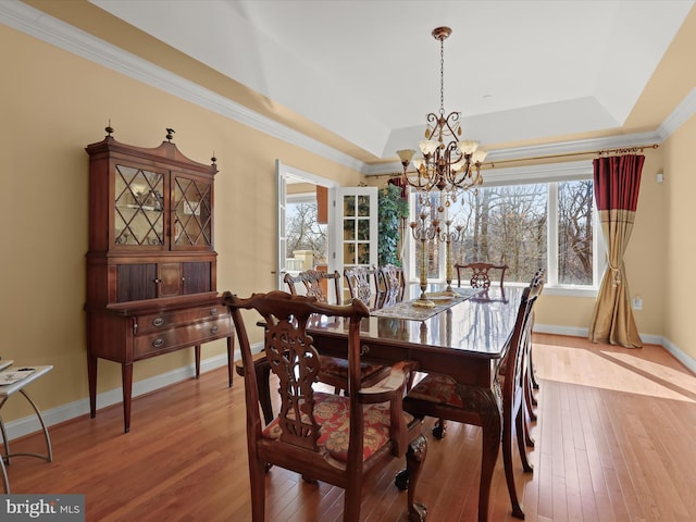 dining room with an inviting chandelier, baseboards, a tray ceiling, and hardwood / wood-style floors