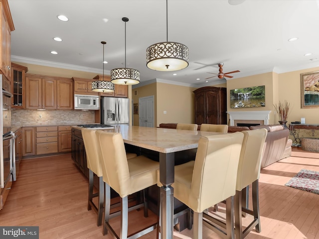 dining room with crown molding, recessed lighting, a fireplace, and light wood finished floors