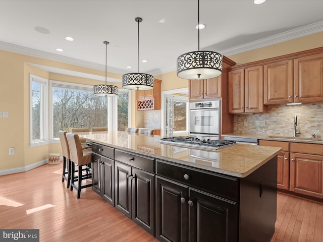 kitchen featuring crown molding, stainless steel appliances, a sink, and a center island