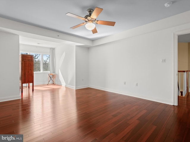 empty room with dark wood-style floors, baseboards, and a ceiling fan