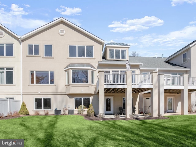 back of property with a standing seam roof, central AC unit, a lawn, and stucco siding