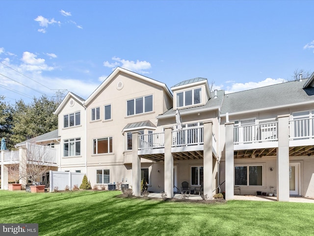 back of property with a standing seam roof, a yard, a patio, and stucco siding