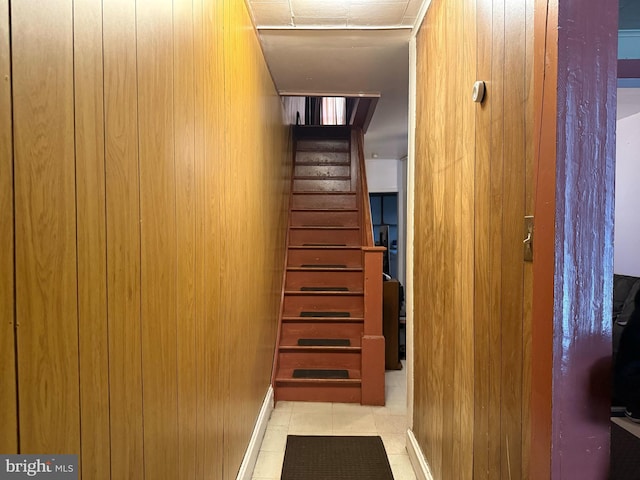 stairway featuring wood walls and tile patterned floors