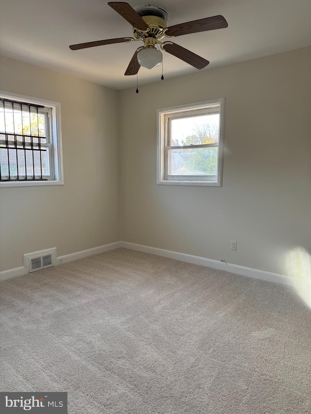 carpeted spare room with a wealth of natural light and ceiling fan