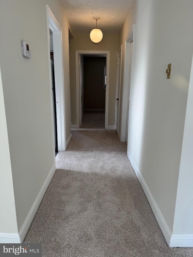 hallway featuring a textured ceiling and light colored carpet