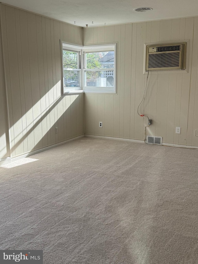 spare room with a wall mounted air conditioner, wooden walls, and light colored carpet