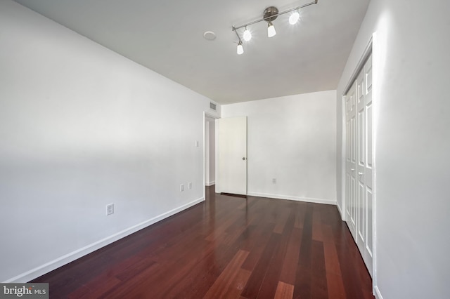 spare room with dark wood-type flooring and track lighting